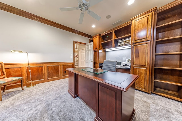 carpeted home office with crown molding, wooden walls, and ceiling fan