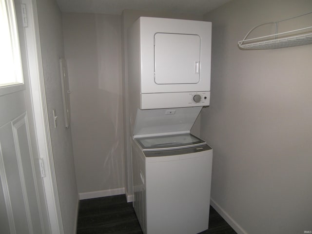 laundry room featuring stacked washer and dryer and dark wood-type flooring