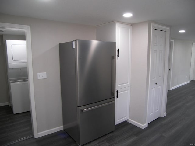 kitchen featuring dark hardwood / wood-style flooring, stacked washer / dryer, and stainless steel refrigerator