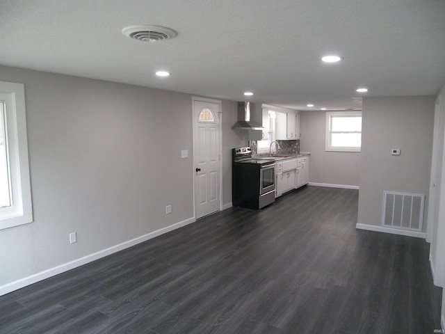 kitchen with stainless steel electric stove, dark hardwood / wood-style floors, white cabinets, and wall chimney range hood