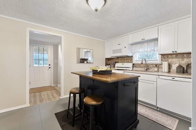 kitchen featuring sink, a kitchen island, white appliances, decorative backsplash, and white cabinets