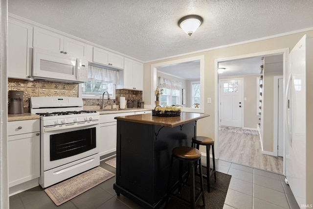 kitchen with white cabinets, decorative backsplash, white appliances, and sink