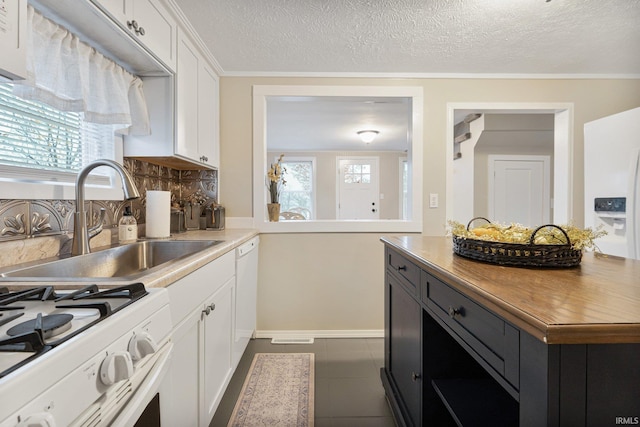 kitchen featuring sink, dark tile patterned floors, a textured ceiling, decorative backsplash, and white cabinets