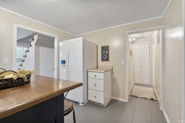 kitchen with white cabinetry, white fridge with ice dispenser, a textured ceiling, light tile patterned floors, and ornamental molding