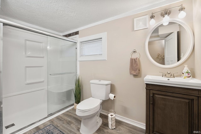 bathroom featuring hardwood / wood-style floors, vanity, toilet, a textured ceiling, and a shower with shower door