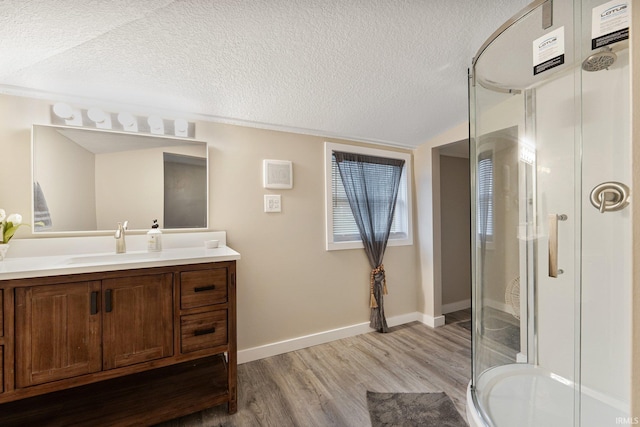 bathroom with a shower with door, vanity, wood-type flooring, and a textured ceiling