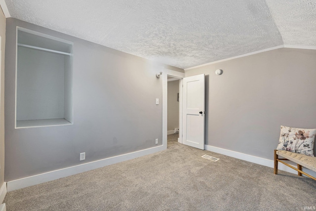 interior space featuring carpet flooring, vaulted ceiling, and a textured ceiling