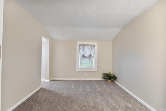 unfurnished room with carpet flooring, a textured ceiling, and vaulted ceiling