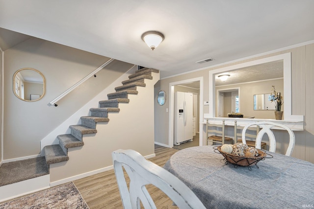 dining space featuring light hardwood / wood-style flooring and crown molding