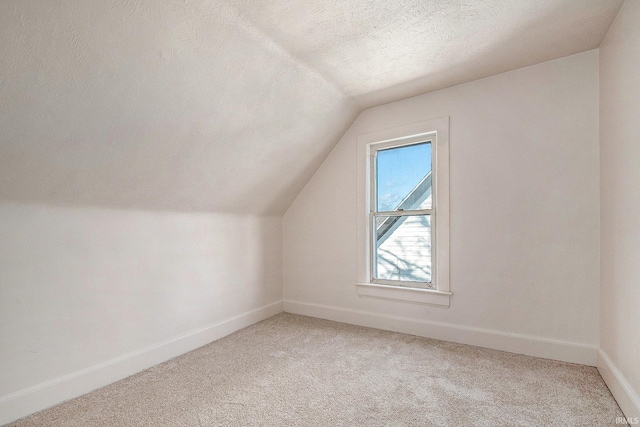 bonus room featuring light carpet, a textured ceiling, and lofted ceiling