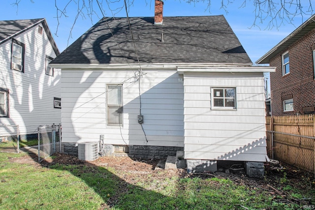 rear view of property with a lawn and central air condition unit