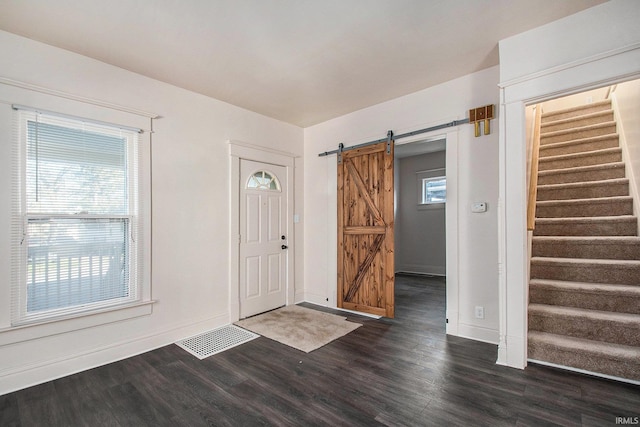 foyer featuring dark hardwood / wood-style floors, a barn door, and a healthy amount of sunlight