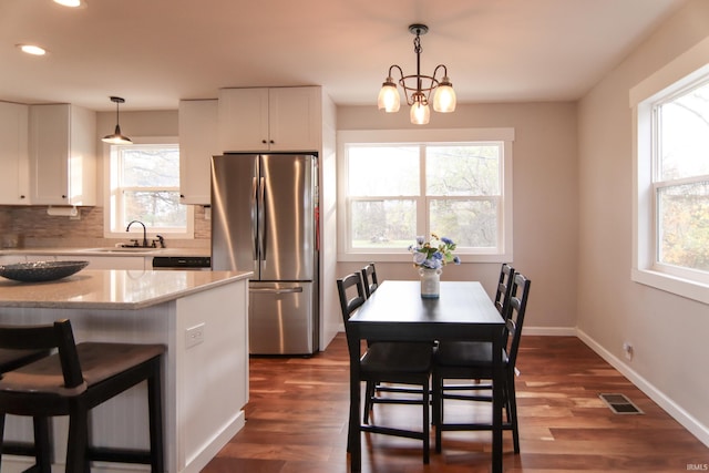 kitchen featuring white cabinets, stainless steel fridge, plenty of natural light, and pendant lighting