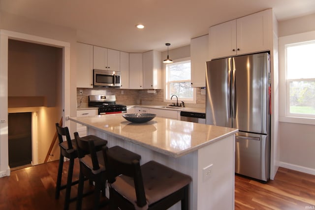 kitchen with sink, white cabinets, decorative light fixtures, and appliances with stainless steel finishes