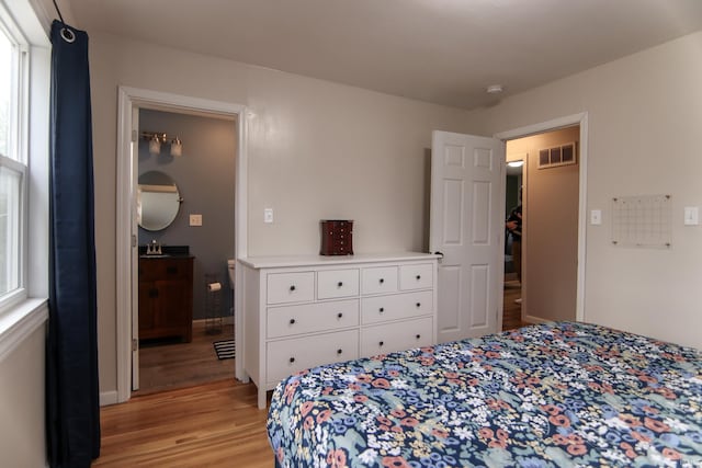 bedroom with light hardwood / wood-style floors and multiple windows