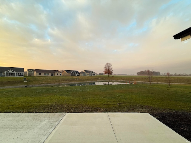 yard at dusk featuring a patio area and a water view