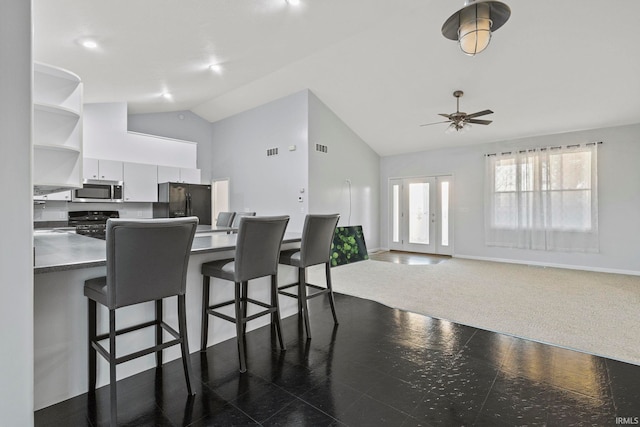 kitchen with dark carpet, black appliances, a kitchen breakfast bar, ceiling fan, and white cabinetry