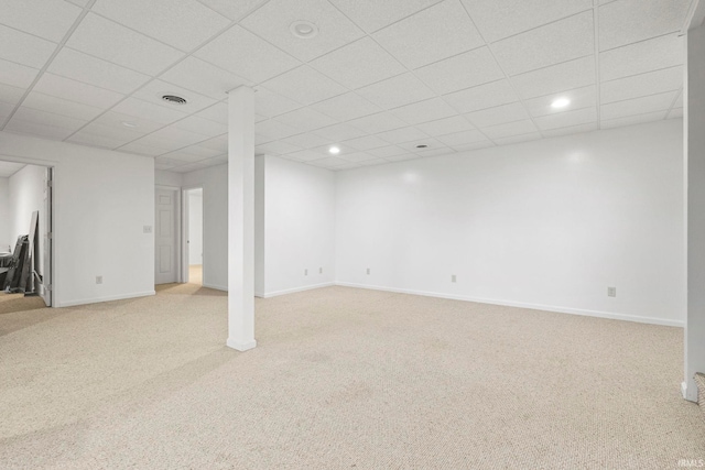 basement with a paneled ceiling and light carpet