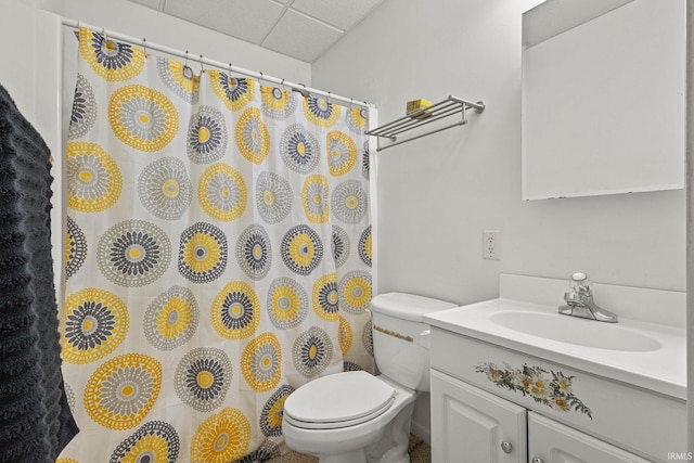 bathroom with a drop ceiling, toilet, and vanity