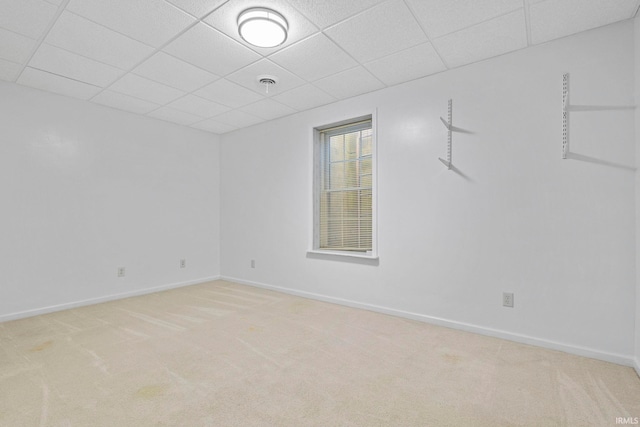 carpeted empty room featuring a drop ceiling