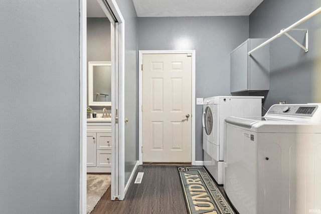 laundry room featuring cabinets, dark wood-type flooring, sink, a textured ceiling, and washing machine and clothes dryer