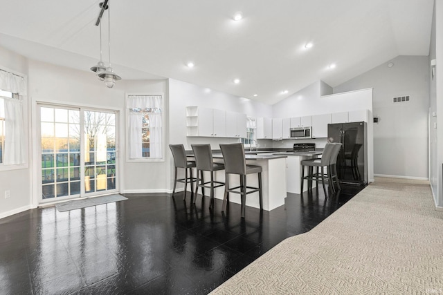 kitchen featuring white cabinetry, sink, high vaulted ceiling, decorative light fixtures, and a kitchen bar