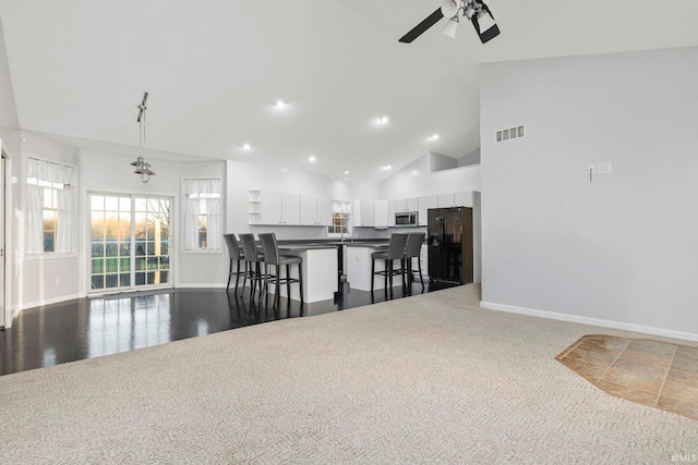 kitchen featuring pendant lighting, a kitchen breakfast bar, black fridge, ceiling fan, and white cabinetry