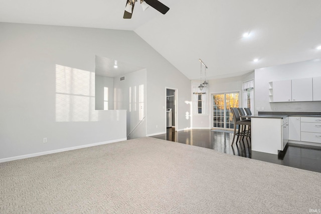 interior space with high vaulted ceiling, dark carpet, and ceiling fan