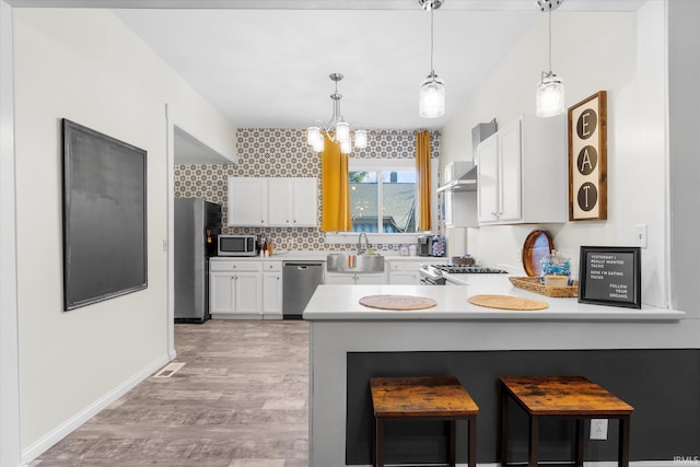 kitchen with white cabinetry, pendant lighting, stainless steel appliances, and sink