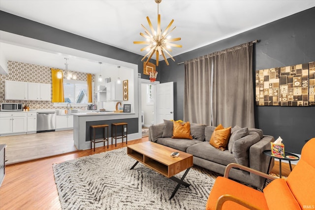 living room with light hardwood / wood-style flooring, a notable chandelier, and sink