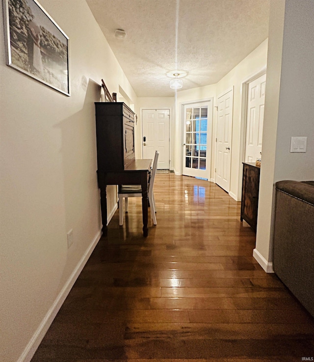 hall featuring dark wood-type flooring and a textured ceiling