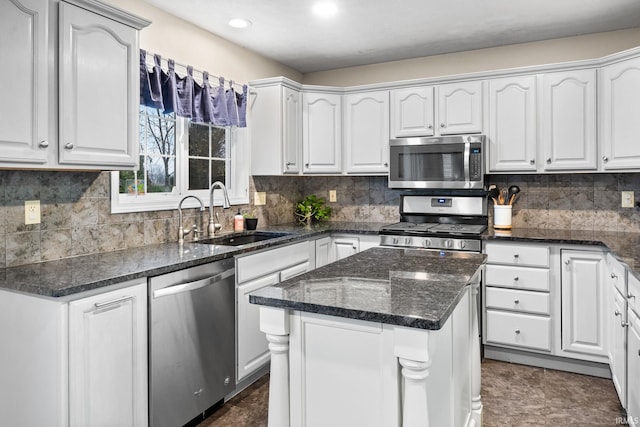 kitchen featuring a center island, dark stone counters, white cabinets, sink, and appliances with stainless steel finishes