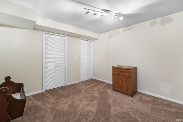 unfurnished bedroom with light colored carpet and track lighting