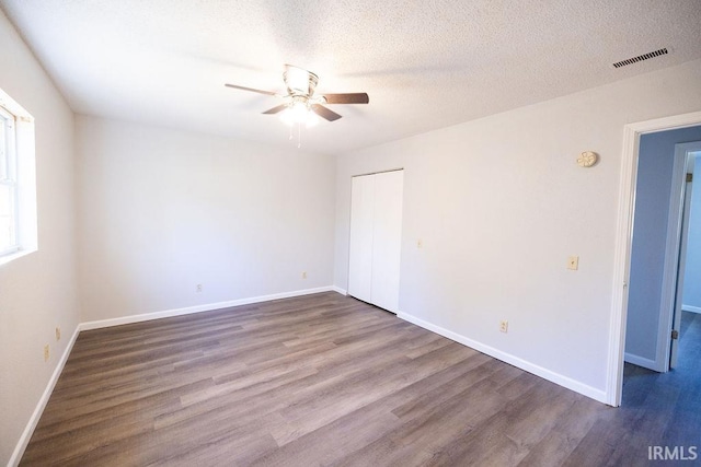 spare room featuring ceiling fan, dark hardwood / wood-style flooring, and a textured ceiling