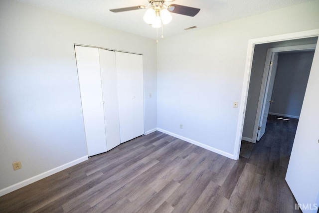 unfurnished bedroom with ceiling fan, dark wood-type flooring, and a closet