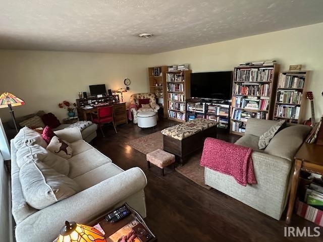 living room with a textured ceiling and dark wood-type flooring