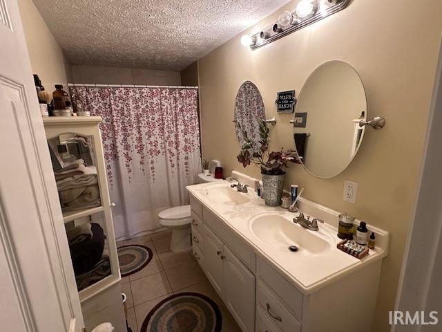 bathroom featuring tile patterned flooring, vanity, a textured ceiling, and toilet