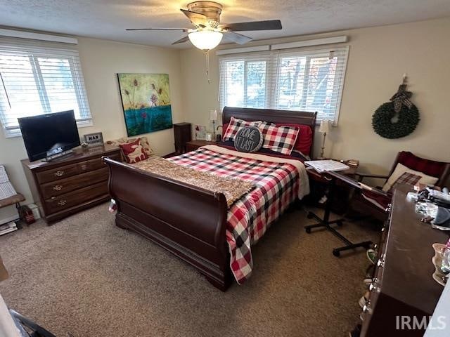 carpeted bedroom with ceiling fan and a textured ceiling