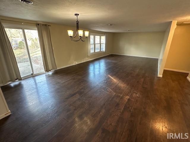 spare room featuring dark hardwood / wood-style flooring and a chandelier