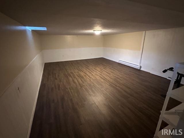 basement featuring baseboard heating and dark hardwood / wood-style floors