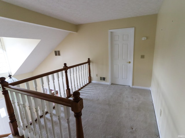 stairway featuring carpet flooring, a textured ceiling, and vaulted ceiling with beams