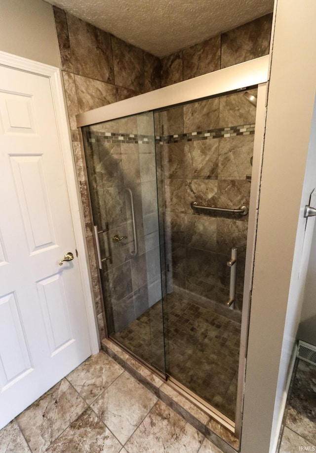 bathroom featuring an enclosed shower and a textured ceiling