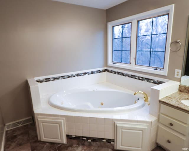 bathroom featuring tiled tub and vanity