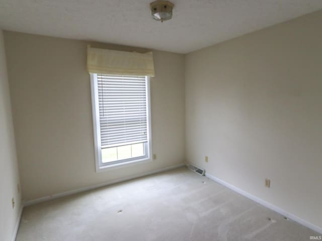 carpeted empty room with a textured ceiling