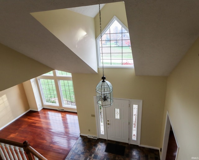 entryway featuring a chandelier, high vaulted ceiling, and dark wood-type flooring