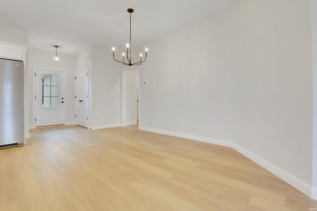 unfurnished dining area with a notable chandelier and light wood-type flooring