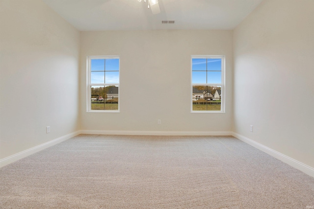 empty room with light carpet, a wealth of natural light, and ceiling fan