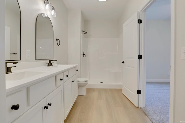 bathroom with vanity, toilet, wood-type flooring, and a shower