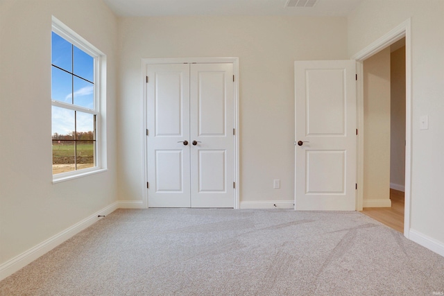 unfurnished bedroom with light colored carpet and a closet