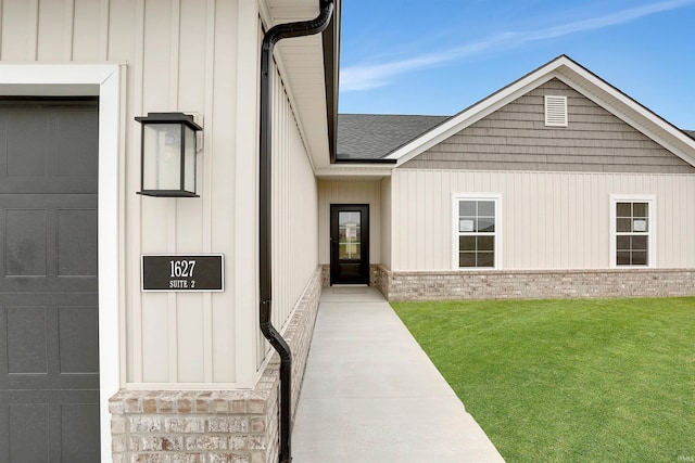 view of exterior entry with a garage and a lawn